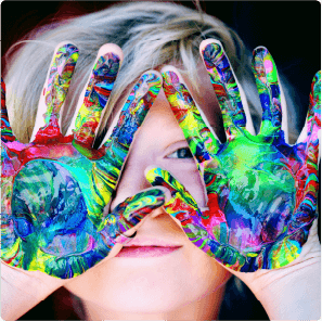 Child with colorful painted hands covering their face